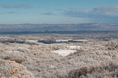 Orman ve puslu uzak tepelerle çevrili köyün rüzgarlı manzarası