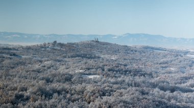 Soğuk kış gecesinden sonra buzla kaplı tepe köyü tepenin üstünde orman ve dağ sıralarıyla çevrili bir kilise var.