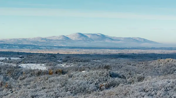 Şafak vakti uzak dağlarla güneş ışığı ve kışın manzarası