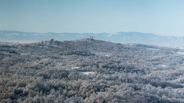 Soğuk kış gecesinden sonra buzla kaplı tepe köyü tepenin üstünde orman ve dağ sıralarıyla çevrili bir kilise var.
