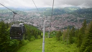 Bulutlu ve yağmurlu bir günde Vlasiç dağından Saraybosna 'ya teleferiğe bin, rüzgar kalkanına yağmur damlaları düşsün