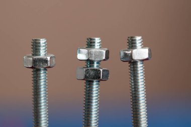 Arka planda fındıklı üç cıvata, ortadakinde iki fındık, diğerinde ise bir tane var.