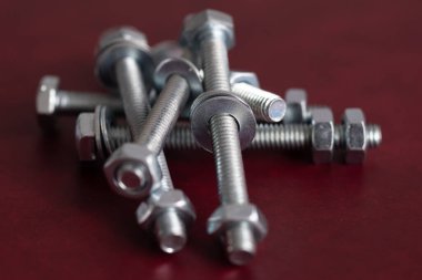 Koyu kırmızı arka planda bir sürü cıvata var, bir cıvatada iki tane conta var.