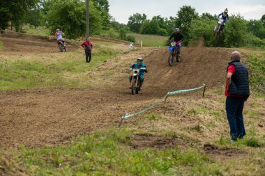 Bulutlu bir günde çamurlu yolda motokros sürücüleri yeteneklerini gösteriyorlar.