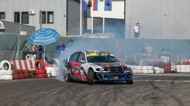 Yanan lastiklerden gelen dumanlar yüzünden araba raylarda sürükleniyor.