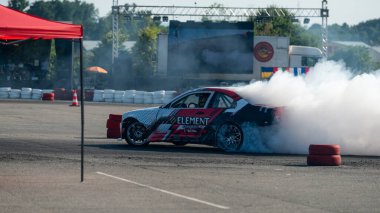 Yanan lastiklerden gelen dumanlar yüzünden araba raylarda sürükleniyor.