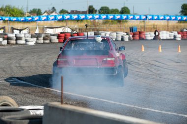 Yanan lastiklerden gelen dumanlar yüzünden araba raylarda sürükleniyor.