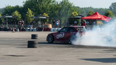 Yanan lastiklerden gelen dumanlar yüzünden araba raylarda sürükleniyor.