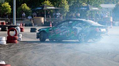 Yanan lastiklerden gelen dumanlar yüzünden araba raylarda sürükleniyor.