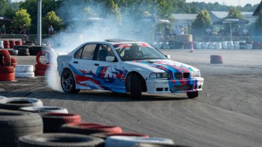 Yanan lastiklerden gelen dumanlar yüzünden araba raylarda sürükleniyor.