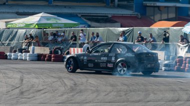 Yanan lastiklerden gelen dumanlar yüzünden araba raylarda sürükleniyor.