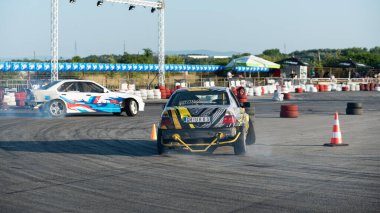 Yanan lastiklerden gelen dumanlar yüzünden araba raylarda sürükleniyor.