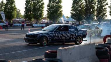 Yanan lastiklerden gelen dumanlar yüzünden araba raylarda sürükleniyor.