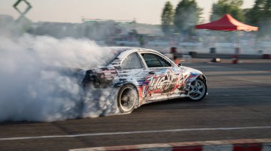 Yanan lastiklerden gelen dumanlar yüzünden araba raylarda sürükleniyor.