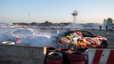 Yanan lastiklerden gelen dumanlar yüzünden araba raylarda sürükleniyor.