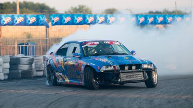 Yanan lastiklerden gelen dumanlar yüzünden araba raylarda sürükleniyor.