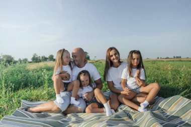 Küçük kızı çim tarlasında yürüyen çiftçi bir aile. Anne baba kız el ele tutuşarak yürüyor. Baba ve küçük kız mavi gökyüzüne karşı buğday tarlasında yürüyorlar. Ebeveynlerinin kızı..
