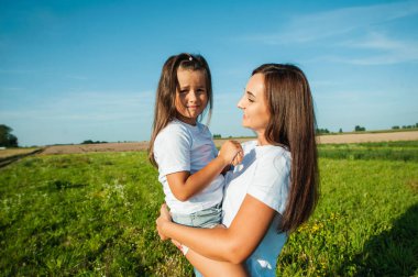 Aile boş zamanlarını temiz havada geçirir. Kız kardeşler eğleniyor. Annesi kucağında bir kız bebeği tutuyor.
