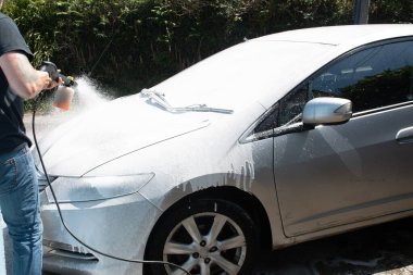 Gümüş rengi bir arabayı yıkayan iki erkek. 