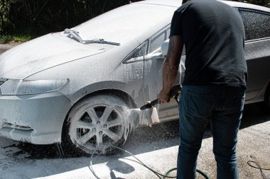 Gümüş rengi bir arabayı yıkayan iki erkek. 