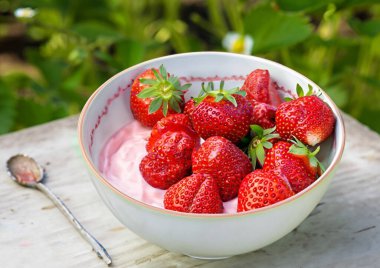 Kremalı bir kasede taze çilek. 