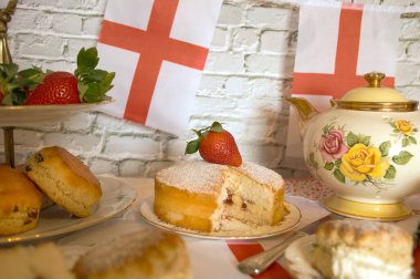 St Georges Günü öğleden sonra çay, klasik geleneksel çörekler çilekler ve kremalı Victoria pastası İngiltere bayrağı. 