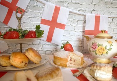 St Georges Günü öğleden sonra çay, klasik geleneksel çörekler çilekler ve kremalı Victoria pastası İngiltere bayrağı. 