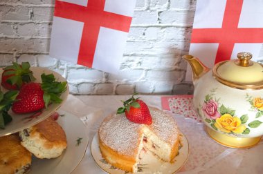 St Georges Günü öğleden sonra çay, klasik geleneksel çörekler çilekler ve kremalı Victoria pastası İngiltere bayrağı. 