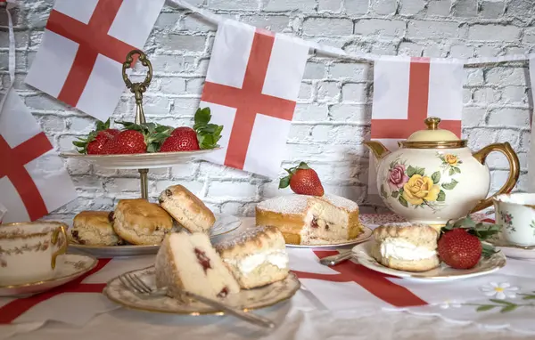 St Georges Günü öğleden sonra çay, klasik geleneksel çörekler çilekler ve kremalı Victoria pastası İngiltere bayrağı. 