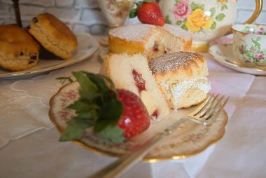 Geleneksel öğleden sonra çayı Vintage tarzı kremalı çörekler çilek ve kremalı geleneksel Victoria usulü sünger klasik porselen tabaklar ve çay fincanları. 