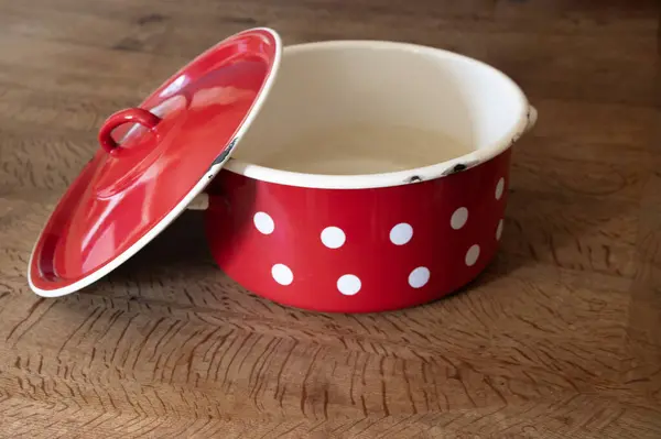 Büyük kırmızı diş mineli polka, ahşap bir masada demlik pişiriyor.