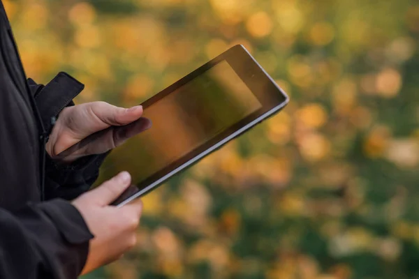 Okulun yanındaki tabletli çocuk internetten öğrenme kitabıyla, çocukların elinde tablet, okul kızı, güzel sarı-yeşil arka plan, bulanık arka plan, bokeh, çevrimiçi eğitim, yan görüş. Yüksek