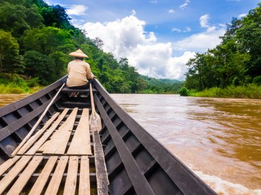 Geleneksel koni şapkalı dümenci uzun kuyruklu teknesi Tayland 'la Pai Nehri' nde yelken açıyor.