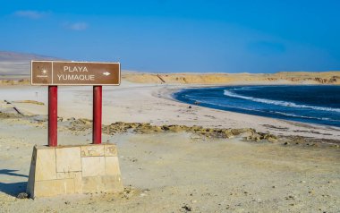 Önünde turistik tabela olan Yumaque Sahili panoramik manzarası, Paracas Ulusal Rezervi, Peru