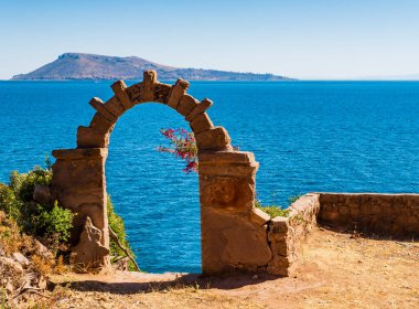 Titicaca Gölü, Puno Bölgesi, Peru 'nun zümrüt sularında göze çarpan tipik taş kemeriyle Taquile adasında etkileyici bir manzara. 
