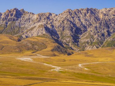 Campo Imperatore Vadisi 'ndeki sarı çayırlar ve kayalık dağlarla muhteşem bir manzara, Gran Sasso Ulusal Parkı, Abruzzo Bölgesi, İtalya 