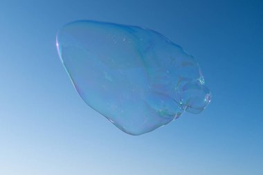 Arka planda büyük sabun köpükleri. Mavi gökyüzünde renkli sabun köpüğü