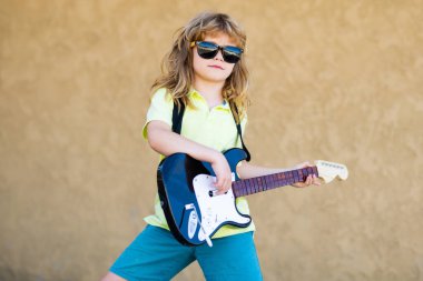 Gitarlı çocuk. Çocuk gitar çalar ve şarkı söyler, çocuklar müzik ve şarkı söyler. Elektro gitar çalan çocuk müzisyen.