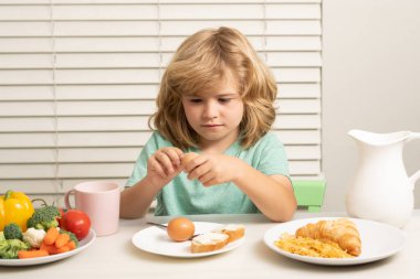 Çocuk yumurta yiyor. Çocuk portresi evde taze sağlıklı yiyecekler yiyor. Çocuk okuldan önce kahvaltı yapıyor.