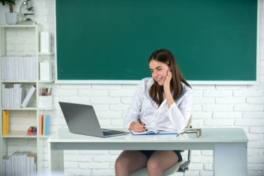 Sınıfta dizüstü bilgisayarla çalışan bir üniversite öğrencisi sınava hazırlanıyor. Serbest çalışan bir kadın ya da bilgisayarlı bir öğrenci.