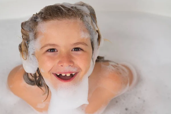 Children bathing. Funny bath. Child with shampoo foam and bubbles on hair taking bath. Portrait of smiling kid, hair care and hygiene concept. Kids shampoo for long hair. Washing hair in bath