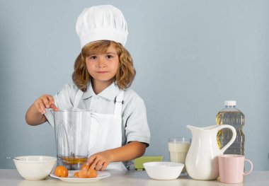 Yemek pişiren çocuklar. Aşçı çocuk sağlıklı yemek için taze sebze yapıyor. Gri arka planda izole edilmiş küçük çocuk portresi. Aşçı çocuk. Yemek pişirme süreci