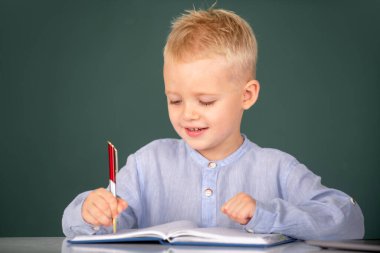 İlkokulda ders sırasında tahtaya yakın bir öğrenci portresi. İlkokulda küçük bir okul çocuğu ders çalışıyor.