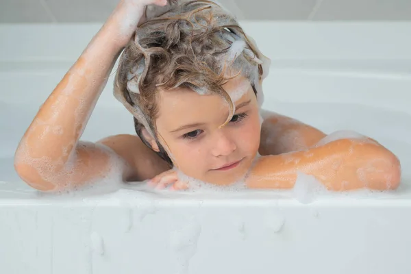 Kids shampoo. Child in the bath with bubbles. Happy child enjoying bath time. Little boy smiling in the bath with soap foam. Child bathes in a bath with foam