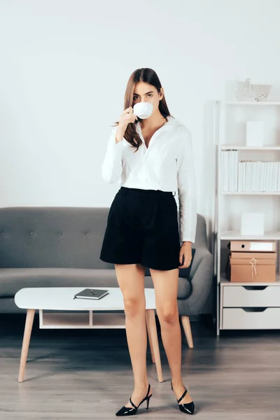 Young businesswoman with cup of coffee with too much work in office. Secretary girl