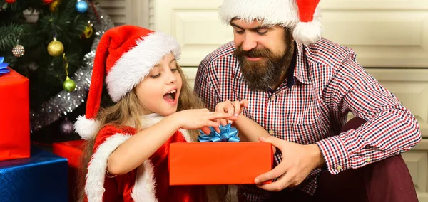 Merry Christmas and Happy Holidays. Father with daughter celebrating christmas. Dad and child open christmas gift. Cheerful father and cute daughter exchanging gifts. Loving family