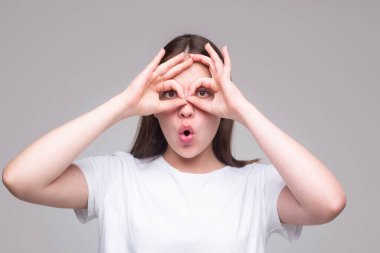 Parmak gözlü komik kadın. Kameraya parmaklarıyla bakan güzel bir kadın modelin portresini yakından çek. Yüz ifadeleri, duygular ve vücut dili