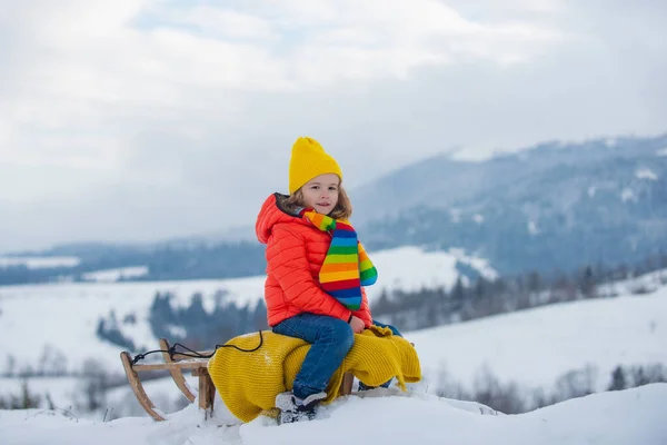 冬の雪の中でそりで滑る男の子 クリスマスの子供の休日とハッピーニューイヤー — ストック写真