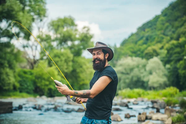 希斯特留胡子的男人钓到鳟鱼 男人拿着钓竿 渔夫在外面的河水里钓鱼 暑期钓鱼业余爱好 — 图库照片