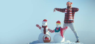 Heyecanlı adam ve kardan adam. Kışın arka planda kardan adam olan harika bir adam. Kış bayrağı için kardan adam. Noel ve yeni yıl kar konsepti, kış mevsimi